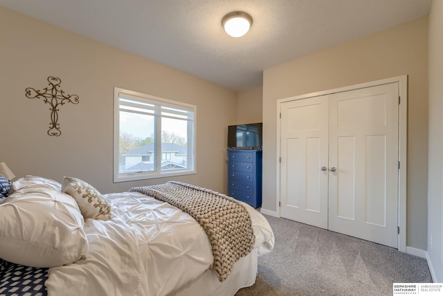 carpeted bedroom featuring baseboards and a closet