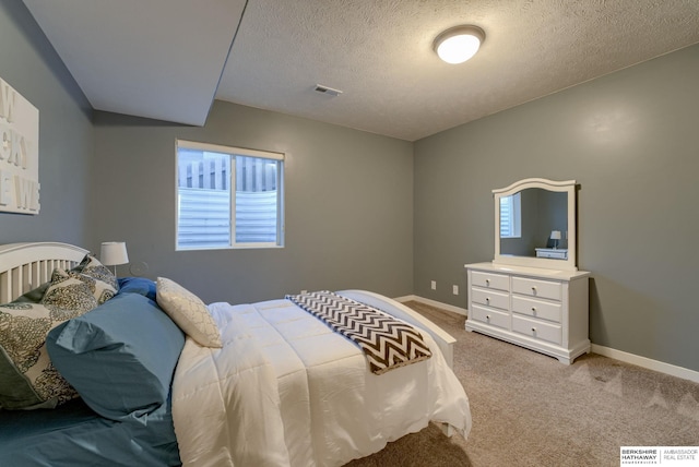 carpeted bedroom with baseboards, a textured ceiling, and visible vents