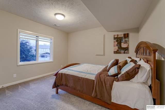 carpeted bedroom featuring baseboards, a textured ceiling, and visible vents