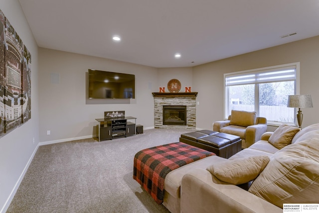 carpeted living area featuring baseboards, a stone fireplace, visible vents, and recessed lighting