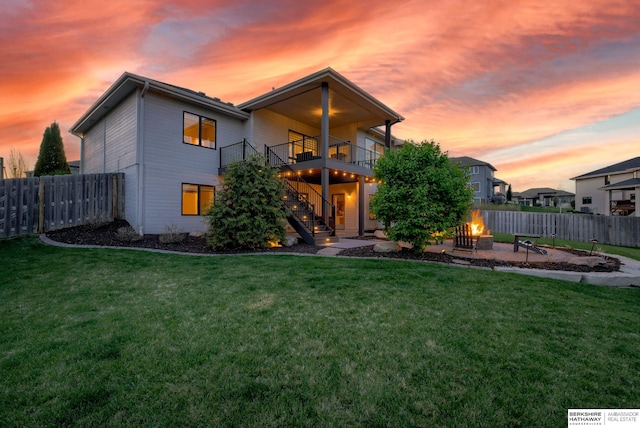 back of property with stairway, a lawn, an outdoor fire pit, and a fenced backyard