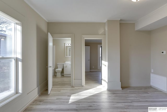 unfurnished room featuring baseboards, ornamental molding, light wood finished floors, and plenty of natural light
