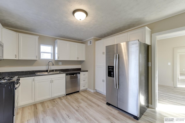 kitchen featuring a sink, light wood-type flooring, white cabinets, appliances with stainless steel finishes, and visible vents