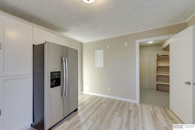 kitchen with white cabinets, baseboards, light wood-type flooring, and stainless steel fridge