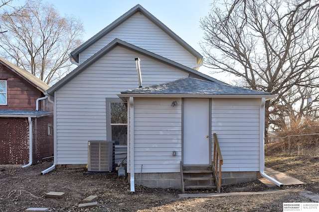 back of property featuring central AC, roof with shingles, fence, and entry steps