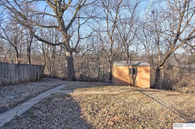 view of yard featuring an outdoor structure, fence, and a storage shed