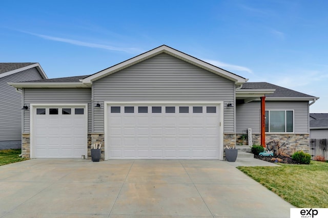 view of front facade with a garage, driveway, stone siding, a front yard, and roof with shingles