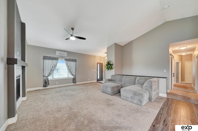 living area with lofted ceiling, light wood-type flooring, baseboards, light colored carpet, and ceiling fan
