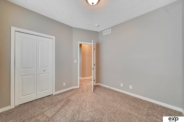 unfurnished bedroom with visible vents, baseboards, carpet flooring, and a closet