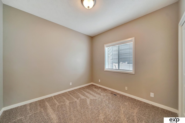 carpeted empty room featuring baseboards and visible vents