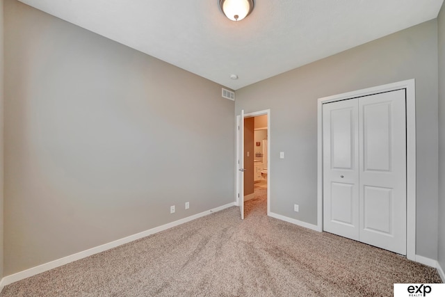 unfurnished bedroom featuring a closet, carpet flooring, baseboards, and visible vents