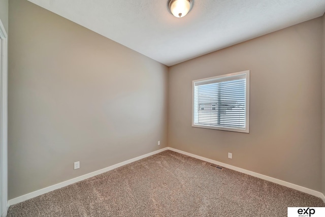 empty room with carpet floors, visible vents, and baseboards