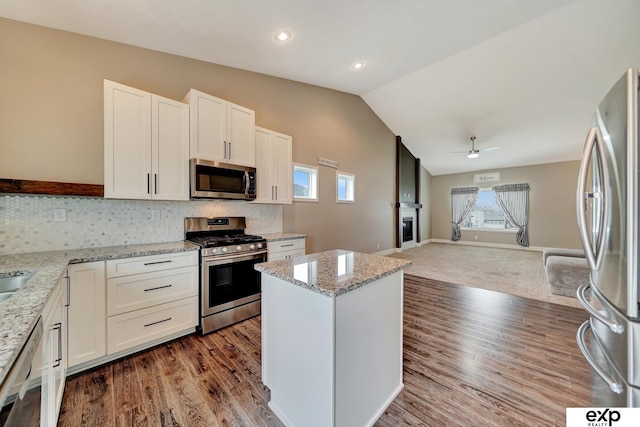 kitchen with open floor plan, ceiling fan, appliances with stainless steel finishes, and a healthy amount of sunlight