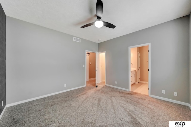 unfurnished bedroom with ensuite bathroom, baseboards, visible vents, a ceiling fan, and carpet floors