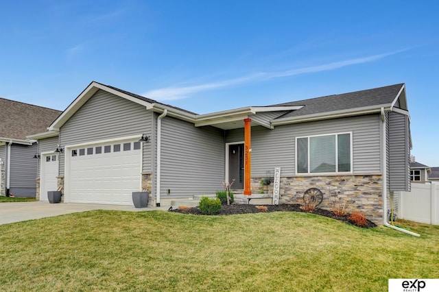 view of front of property with concrete driveway, a front lawn, stone siding, an attached garage, and fence