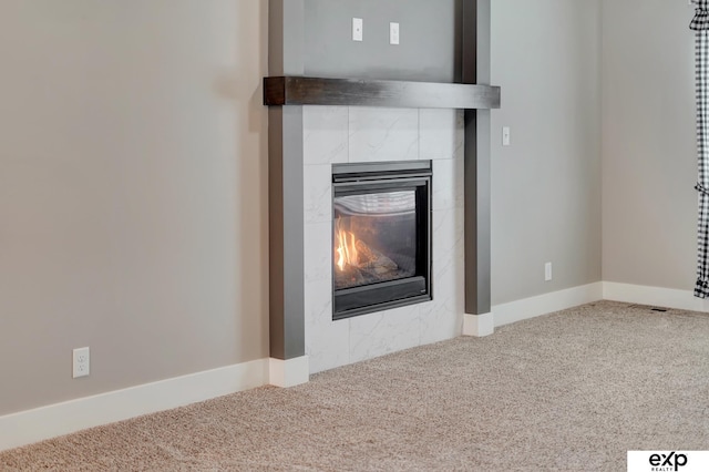 room details featuring a tiled fireplace, carpet flooring, and baseboards