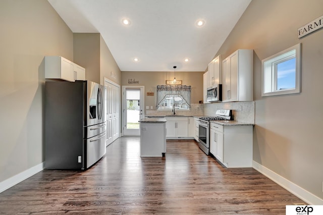 kitchen featuring stainless steel appliances, a sink, tasteful backsplash, white cabinetry, and a kitchen island