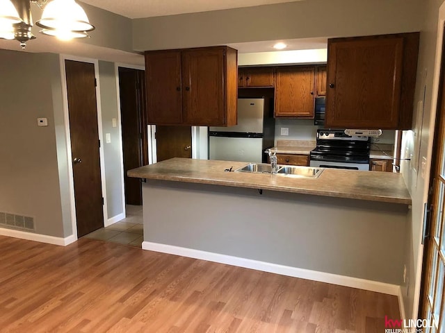 kitchen featuring light wood finished floors, visible vents, a sink, baseboards, and appliances with stainless steel finishes