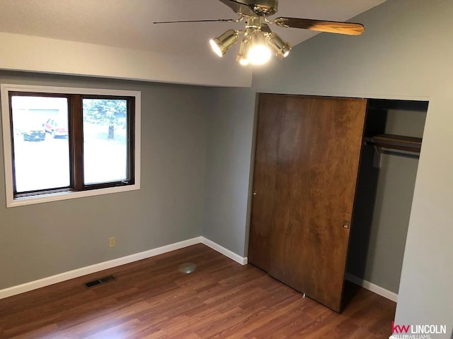 unfurnished bedroom featuring wood finished floors, visible vents, a closet, baseboards, and ceiling fan