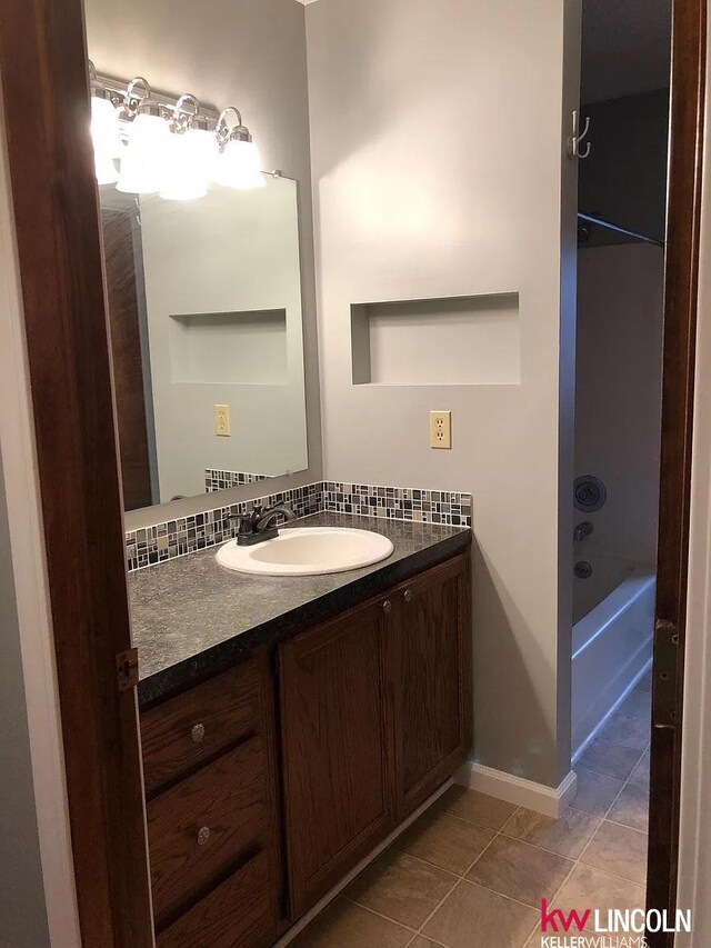 full bath with tile patterned flooring, baseboards, and vanity