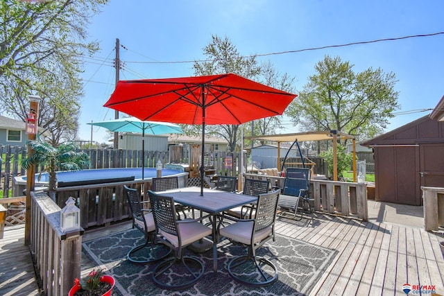 wooden terrace featuring a storage shed, an outbuilding, outdoor dining area, and a fenced backyard