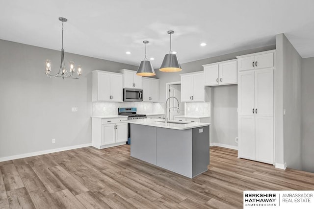 kitchen with recessed lighting, light wood-type flooring, stainless steel appliances, and a sink