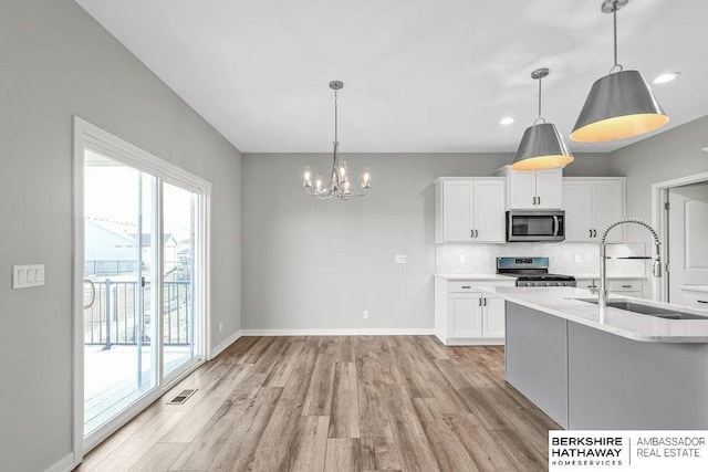 kitchen featuring white cabinets, visible vents, a sink, light wood-style floors, and appliances with stainless steel finishes