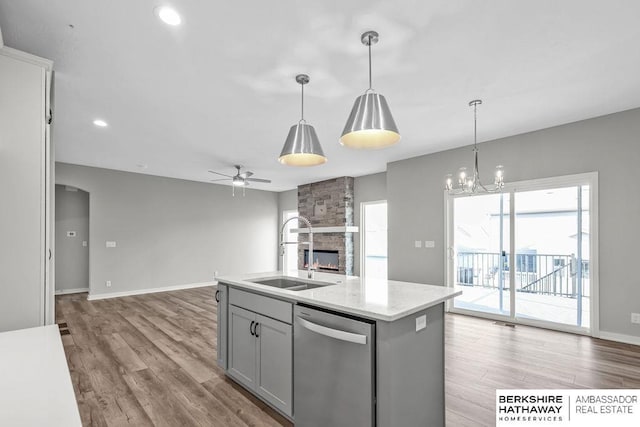 kitchen with a sink, open floor plan, ceiling fan with notable chandelier, gray cabinetry, and dishwasher