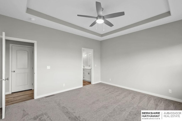 unfurnished bedroom with visible vents, baseboards, carpet flooring, and a raised ceiling