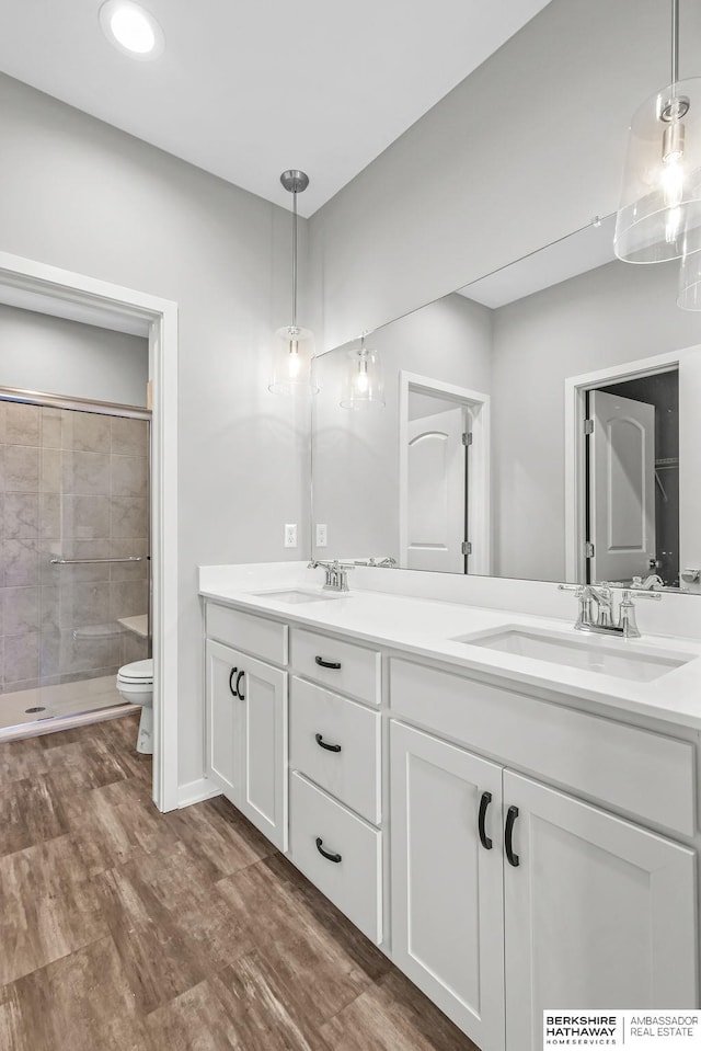 full bath featuring a tile shower, double vanity, toilet, and a sink
