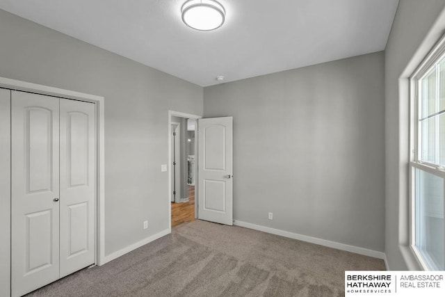 unfurnished bedroom featuring carpet floors, a closet, and baseboards