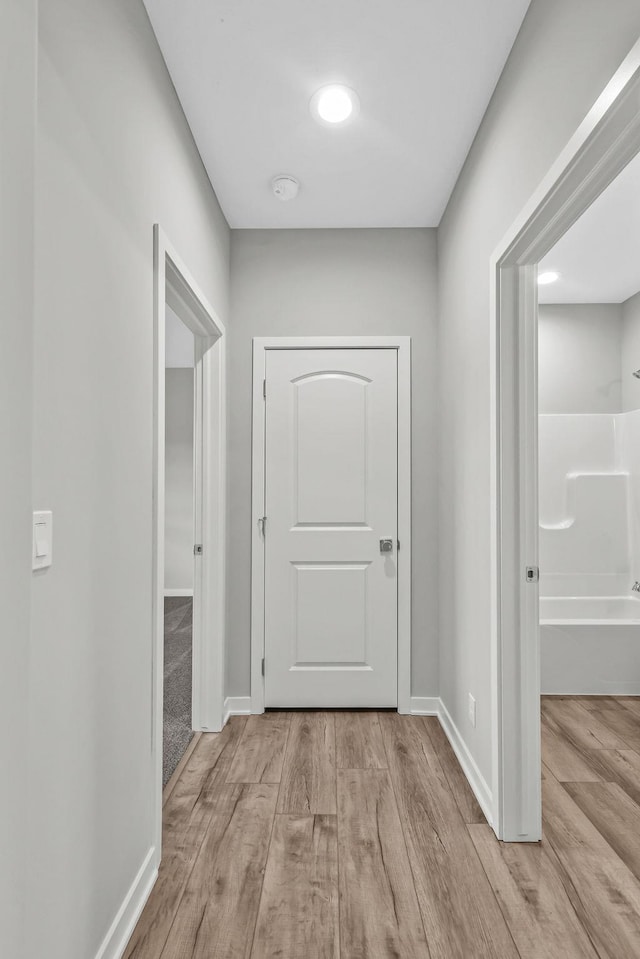 hallway featuring baseboards and wood finished floors