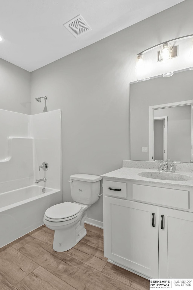 bathroom with wood finished floors, visible vents, shower / bath combination, toilet, and vanity