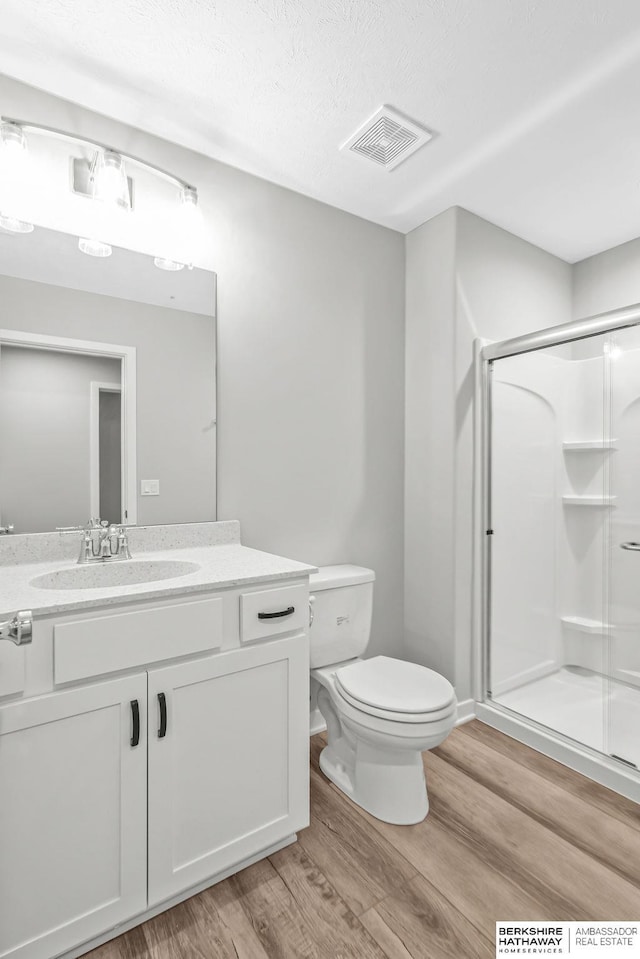 full bathroom featuring wood finished floors, visible vents, toilet, and a stall shower