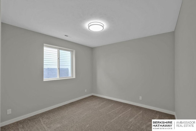 empty room with baseboards, dark colored carpet, and visible vents