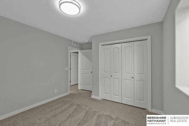unfurnished bedroom with carpet floors, a closet, baseboards, and visible vents