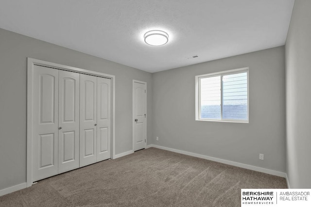 unfurnished bedroom featuring baseboards, carpet flooring, visible vents, and a closet