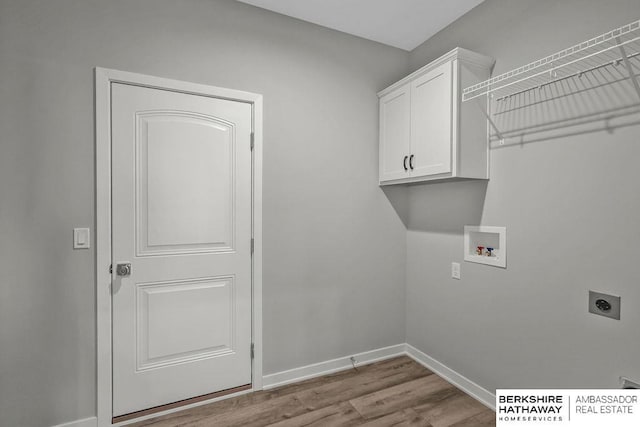 laundry room featuring wood finished floors, hookup for a washing machine, electric dryer hookup, cabinet space, and baseboards