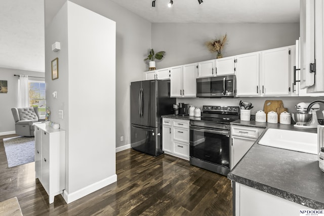 kitchen featuring dark countertops, a sink, stainless steel appliances, white cabinets, and dark wood-style floors