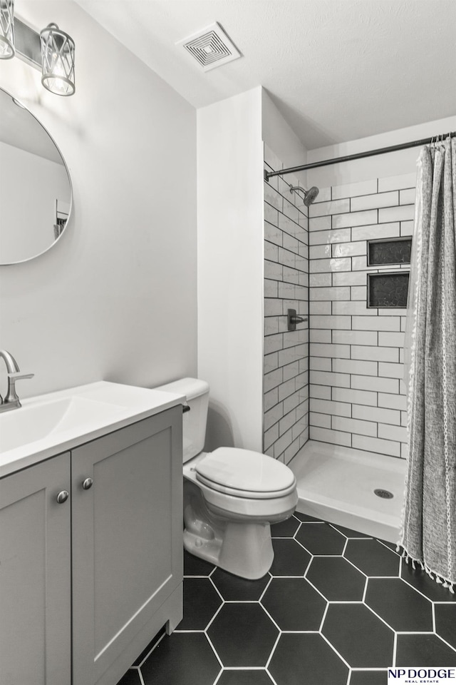 full bathroom with a tile shower, tile patterned floors, visible vents, toilet, and vanity