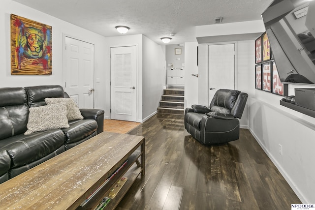 living area with baseboards, wood finished floors, visible vents, and stairs