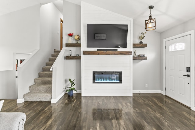 foyer entrance with a large fireplace, stairway, baseboards, and wood finished floors