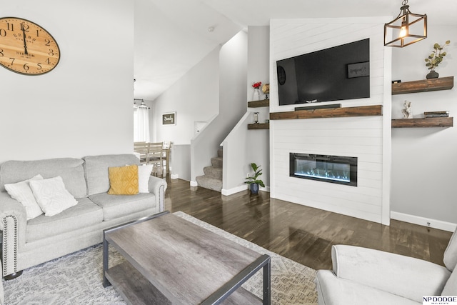 living room featuring lofted ceiling, baseboards, wood finished floors, and a chandelier
