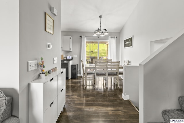 dining space with lofted ceiling, dark wood-type flooring, baseboards, and a notable chandelier