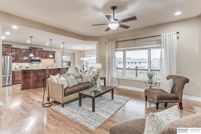living room featuring recessed lighting, baseboards, ceiling fan, and light wood-type flooring