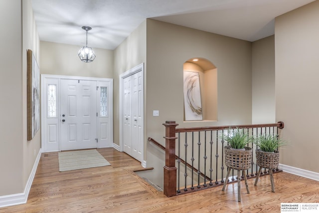 foyer with baseboards, wood finished floors, and a notable chandelier