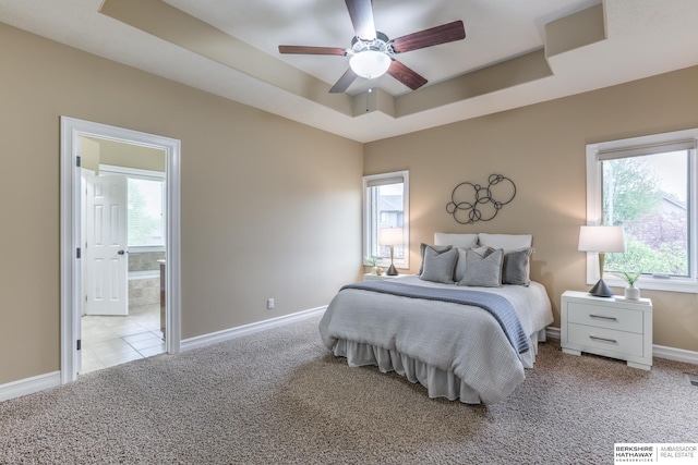 bedroom featuring a tray ceiling, multiple windows, baseboards, and carpet