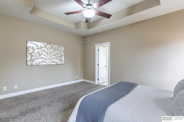 carpeted bedroom with baseboards, ceiling fan, a tray ceiling, and visible vents
