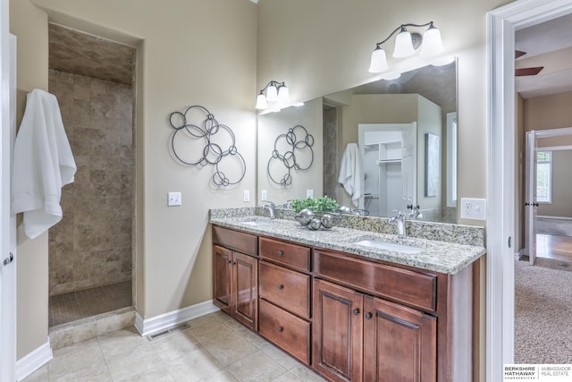 full bathroom with a walk in shower, double vanity, baseboards, and a sink