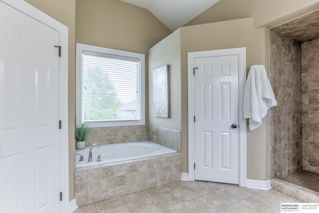 bathroom with tile patterned floors, vaulted ceiling, a tile shower, and a garden tub